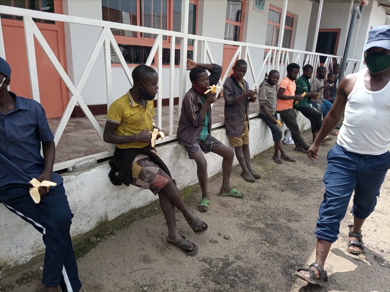 Children and young people sharing bananas outside a building