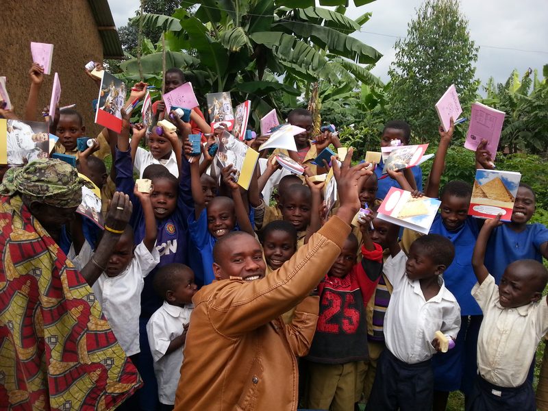Smiling children holding up new exercise books, pens and bars of soap