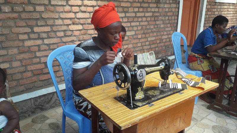 A woman threading a needle at a sewing machine